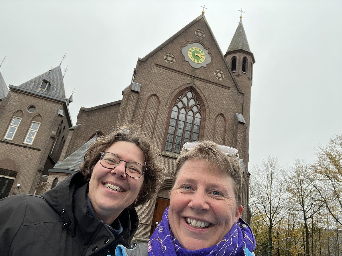 Franciska en Cecille kijken lachend, achter hen de gevel van het klooster